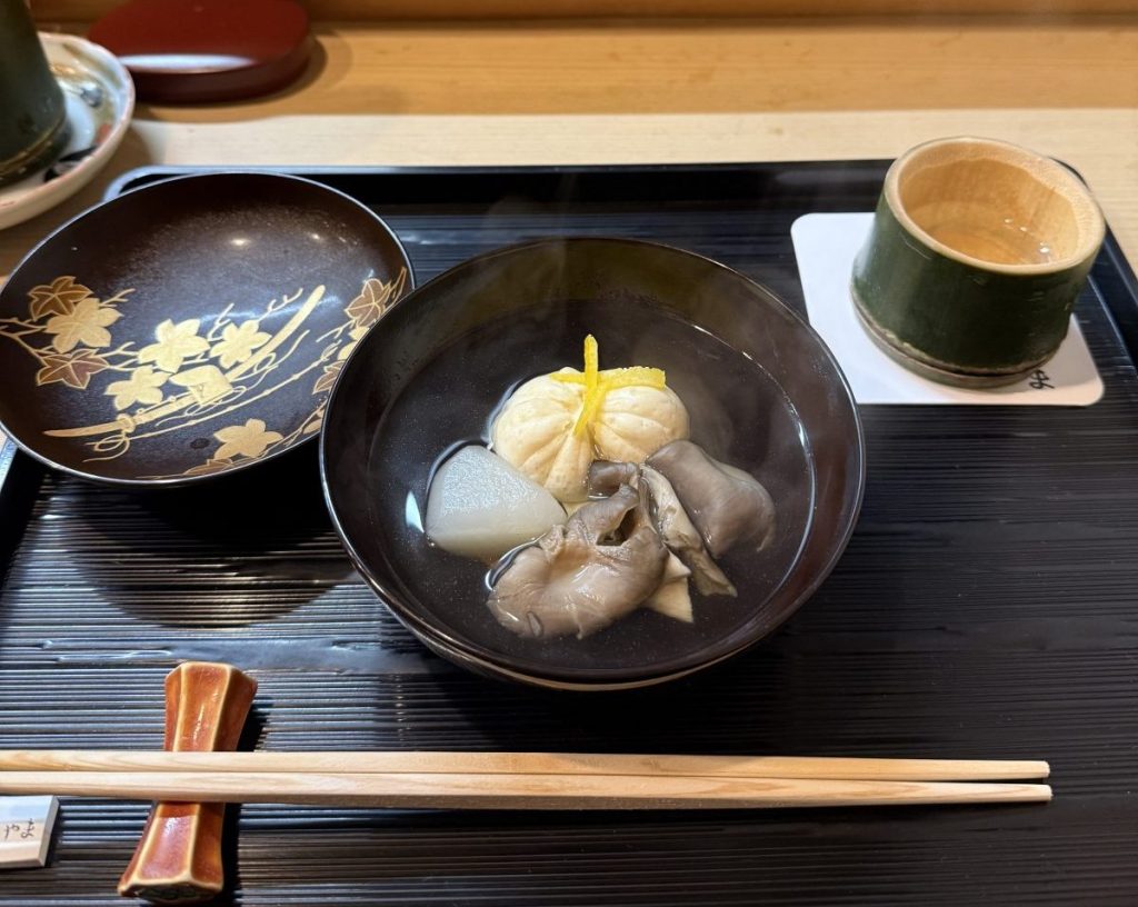 美しい皿に盛られたスープと具材、蒸し物、箸が添えられている。