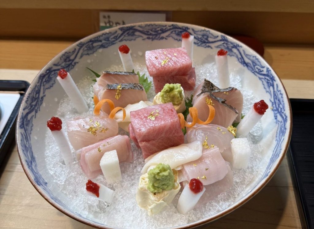 美しい刺身盛り合わせ。新鮮な魚の切り身が氷の上に盛られており、金箔やわさびが添えられている。