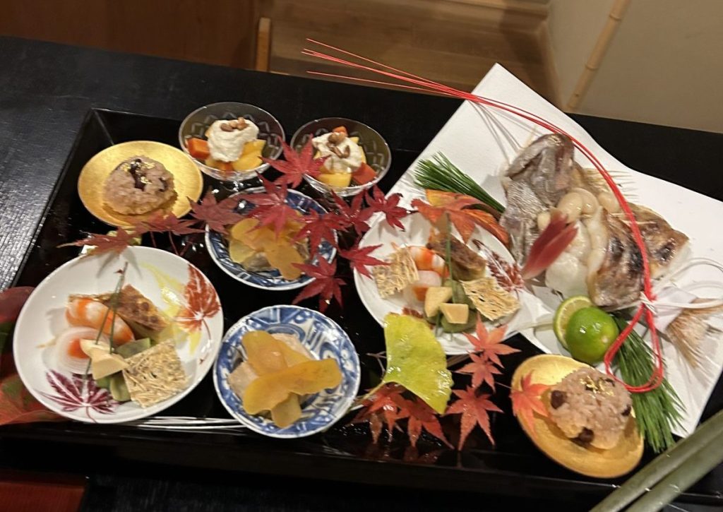 日本料理の盛り合わせ。色とりどりの食材とともに、美しい紅葉が飾られている。
